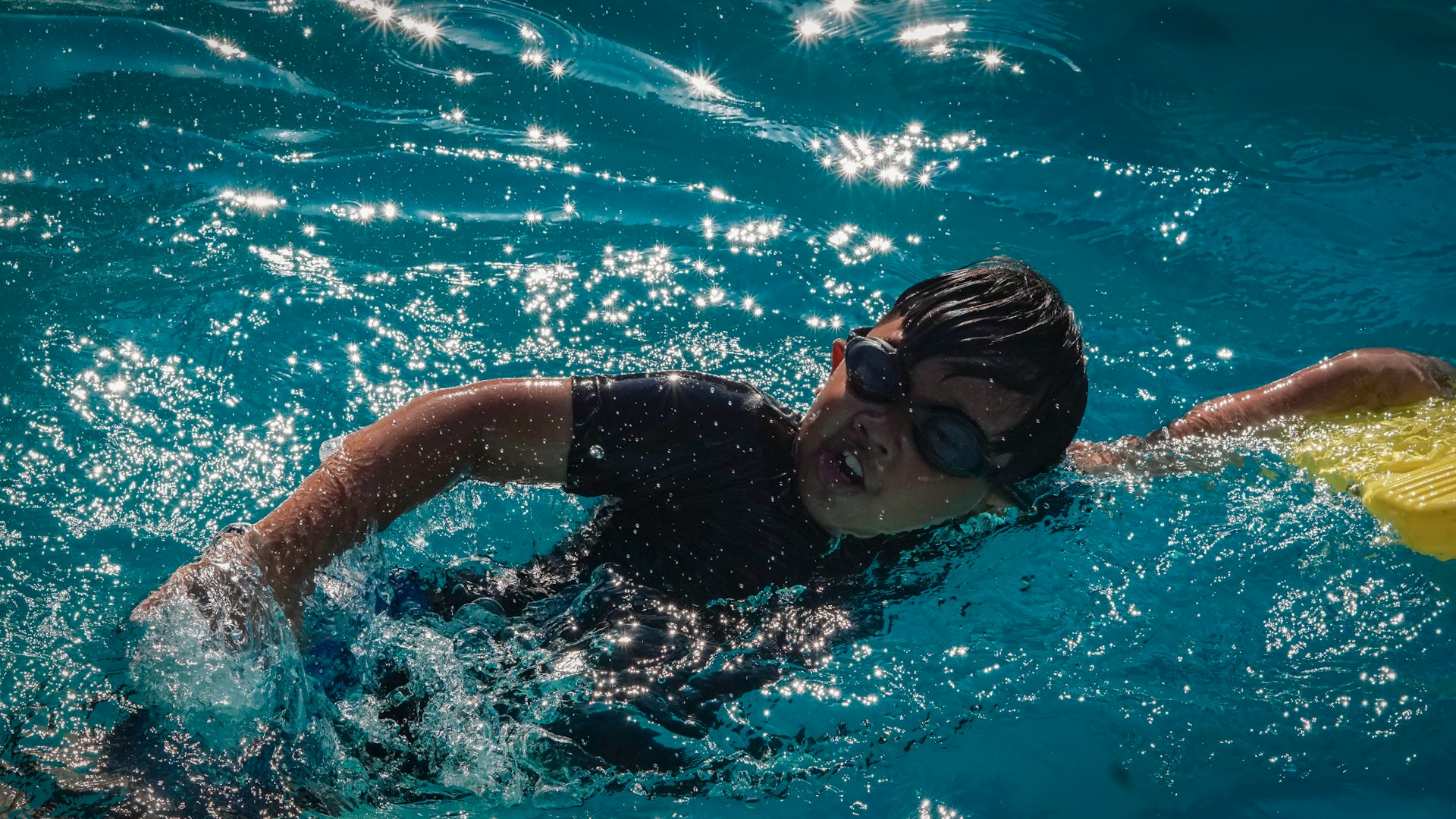 A young boy swims laps in a pool.